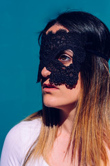 Vertical portrait of attractive young woman with black mask on her face and white shirt, serious gesture, to keep her privacy.