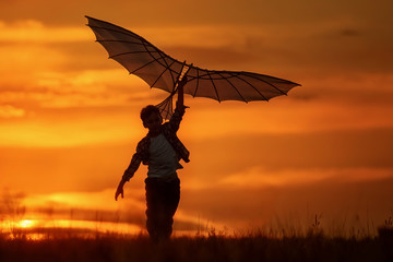 Boy with a kite at sunset