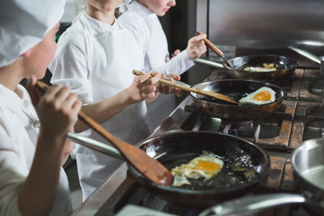 Children cook eggs in the kitchen at the Restaurant.