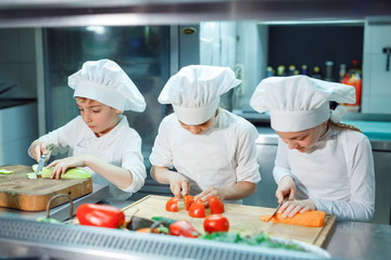 Children grind vegetables in the kitchen.
