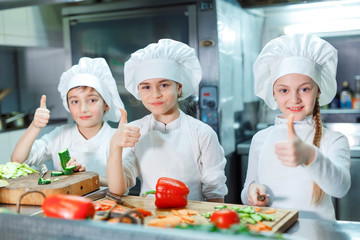 Children grind vegetables in the kitchen.