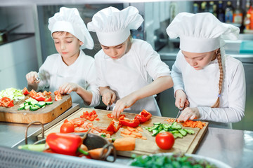 Children grind vegetables in the kitchen.