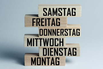 A list of wooden blocks lying on top of each other with a list of days of the six-day work week in German, in the translation of the word: saturday, friday, thursday, wednesday, tuesday, monday