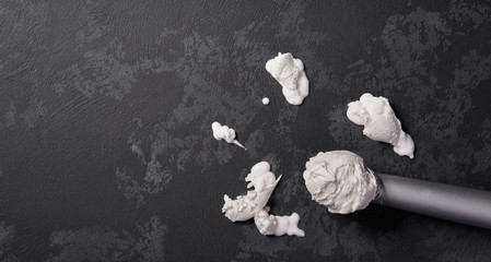 Metal spoon of vanilla ice cream on black background, with copy space.