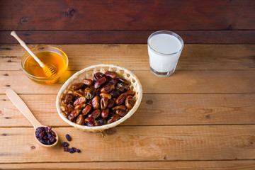 Dried dates, milk and honey on wooden background. Holy month of Ramadan, concept. Righteous Muslim lifestyle. Starvation. Dates in a wooden basket and raisins in the style of minimalism