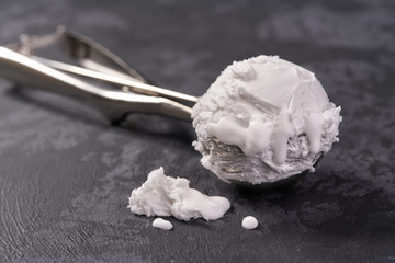 ice cream scoop filled with vanilla ice cream on dark background, selective focus.