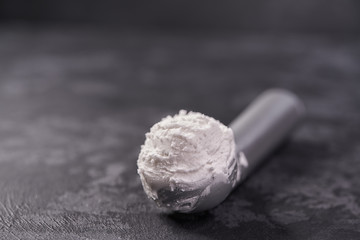 Fototapeta na wymiar ice cream scoop filled with vanilla ice cream on dark background, selective focus.