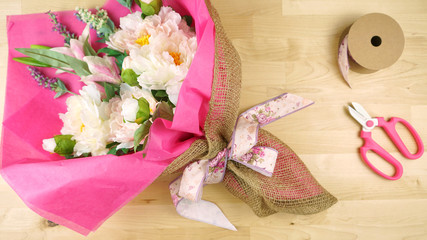 Flowers wrapped in pink tissue and hessian modern trend wrapping flat lay for Mother's Day, birthday or Valentine's Day celebrations.