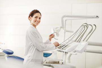 Waist up portrait of confident female dentist smiling at camera while adjusting dental chair , copy space - Powered by Adobe