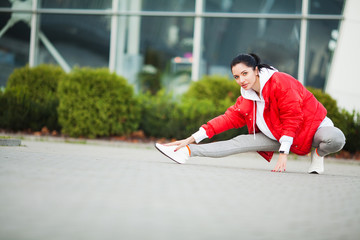 Fitness girl. Young sports woman stretching in the modern city. Healthy lifestyle in the big city