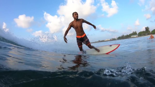 Maldivian surfer rides the ocean tropical wave. Clip contains underwater view of the surfer