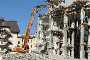 Demolition of building with excavator-destroyer for high-altitude work. Grab crane with hydraulic...