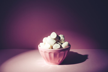 Pink bowl of giant marshmallows on pink backdrop with harsh shadows