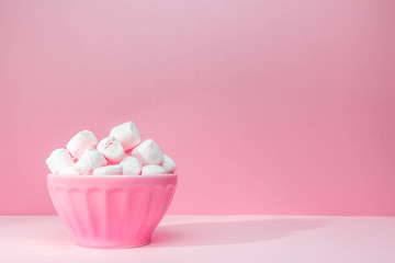 Pink bowl of giant marshmallows on pink backdrop with harsh shadows
