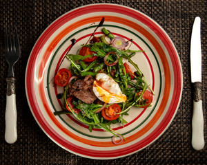 Healthy Breakfast with Poached Egg, Green Salad, cherry tomatoes and beef tongue on black background. Studio shot