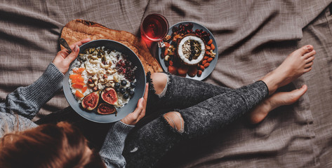 Woman in woolen sweater and jeans eating vegan Rice coconut porridge with figs, berries, nuts. Healthy breakfast ingredients. Clean eating, vegan food concept - obrazy, fototapety, plakaty