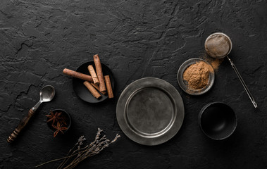 Mix of spices for baking cakes in bowl and spoon, cinnamon, star anise, hazelnuts, walnuts, wheat, lavender on dark stone table. Organic food, top view, space for text