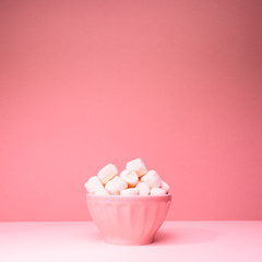 Pink bowl of giant marshmallows on pink backdrop with harsh shadows