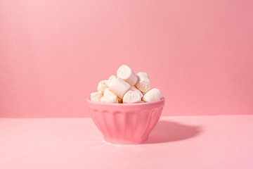 Pink bowl of giant marshmallows on pink backdrop with harsh shadows