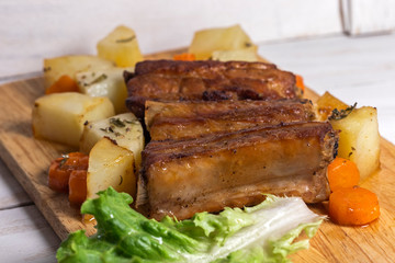 Roasted pork ribs with thyme potatoes over white wooden background, Eastern cuisine