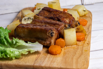 Roasted pork ribs with thyme potatoes over white wooden background, Eastern cuisine
