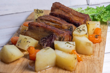 Roasted pork ribs with thyme potatoes over white wooden background, Eastern cuisine