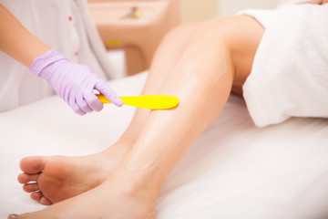 Obraz na płótnie Canvas Skin Care. Hair removal on the legs, laser procedure at clinic. Beautician removes hair on beautiful female legs using a laser