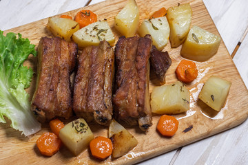Roasted pork ribs with thyme potatoes over white wooden background, Eastern cuisine