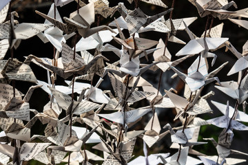 Sunlight across origami paper cranes strung together, very close view, horizontal aspect