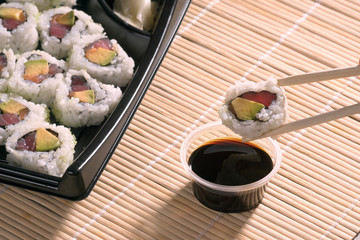 Sushi was taken with special wooden chopsticks and dipped in soy sauce. Near the box with sushi.