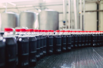 Bottling factory - Black juice bottling line for processing and bottling juice into bottles. Selective focus.