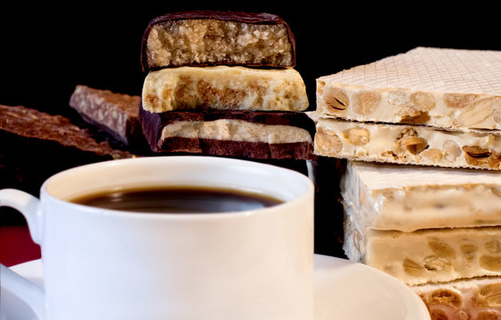 Cup of coffee and turron. Traditional Spanish Christmas candy. Selective focus. Blurred background.