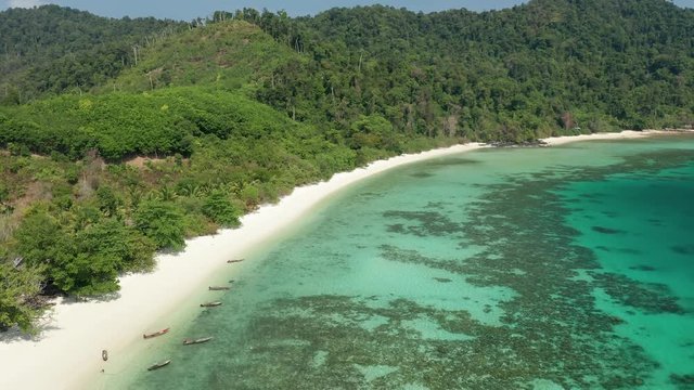 Aerial drone view flying along a tropical island with sandy beach and traditional wooden boats (Swinton Island, Myanmar)
