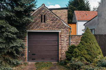 Traditional european garage with red brick and brown gate
