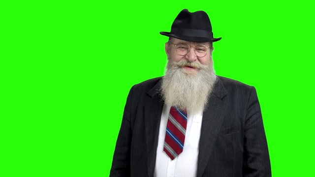 Old smiling businessman on green screen. Friendly bearded senior man in hat and business suit. Alpha Channel background.