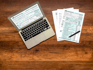 Obraz premium U.S. Individual income tax return on wooden table. Individual income tax return form online on laptop screen.