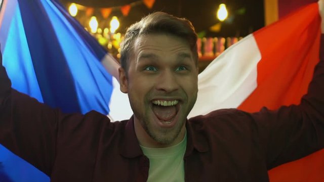 Extremely happy fan waving flag of France rejoicing national sports team victory