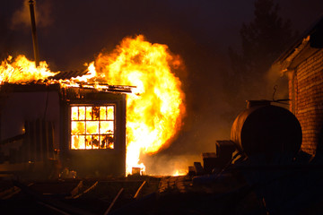 The building is on fire. The house is burned in the fire in the evening. Flames destroy the building at night.