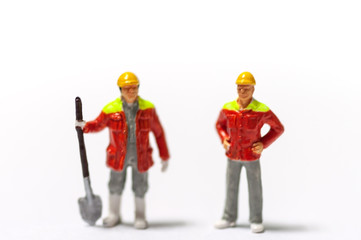 Selective focus miniature workers with yellow safety helmet and orange jacket uniform.  Industrail business conception.