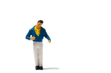 Selective focus miniature figure man wearing blue jacket yellow t-shirt and white long trousers standing in character with copy space.