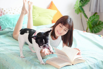 gentle girl in casual wear with a pug puppy in the bedroom on the bed, bright daylight and light toning