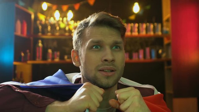 Emotional fan holding flag of France, disappointed about national team defeat