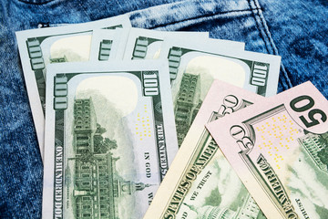 Paper banknotes of American dollars lie on the blue worn jeans.