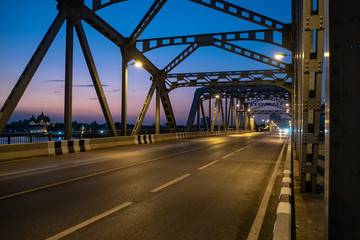 Fototapeta na wymiar Empty old steel structure bridge over the river on clear twilight sky background