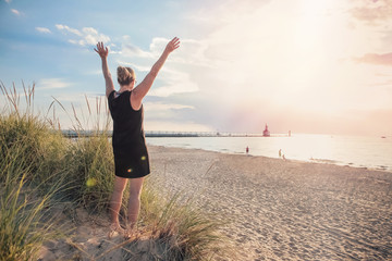 Woman with her arms raised on a dune at the beach
