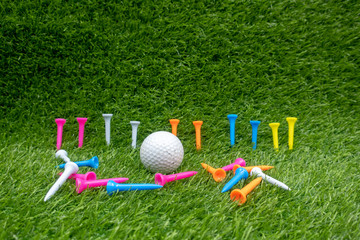 Naklejka premium Golf ball with colourful tees are on green grass