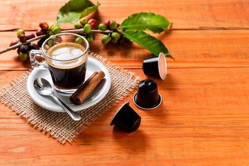 Glass of clear glass of hot coffee on wooden table. Orange wood pinus.