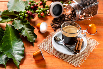 Glass of clear glass of hot coffee on wooden table. Orange wood pinus.