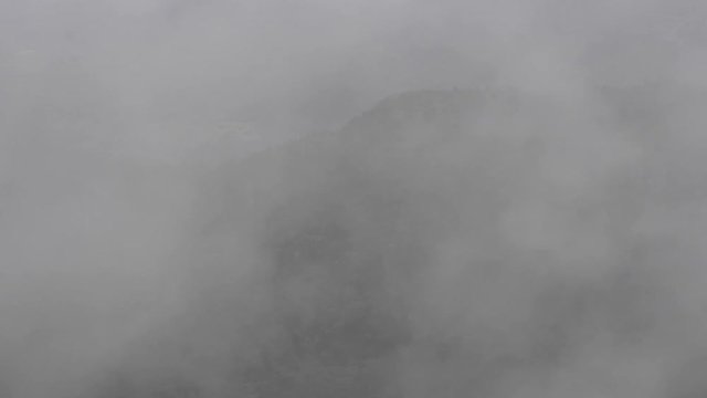 The clouds are moving up from the peaks. The video was shot from a viewpoint looking down on raising clouds. In the background, peaks can been seen through the clouds. This was shot at a hill station.