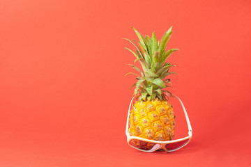 Ripe pineapple in sunglasses on a trendy coral background. Summer holiday concept. Minimalism. Horizontal frame.